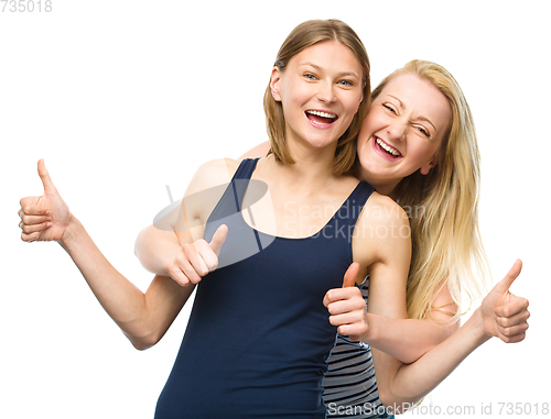 Image of Two young happy women showing thumb up sign