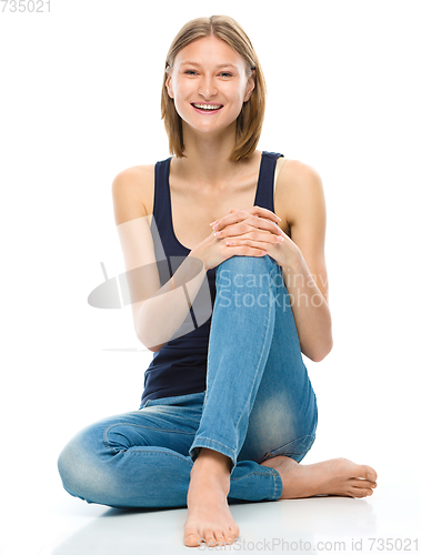 Image of Young happy woman is sitting on the floor
