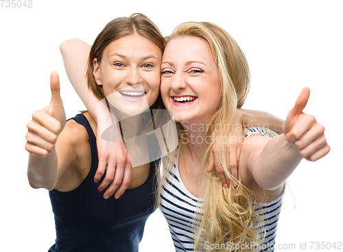 Image of Two young happy women showing thumb up sign