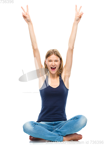 Image of Young happy woman is sitting on the floor