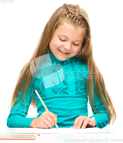 Image of Little girl is drawing using pencils