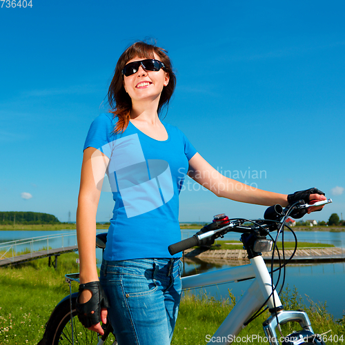 Image of Young woman is standing in front of her bicycle