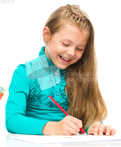 Image of Little girl is drawing using pencils