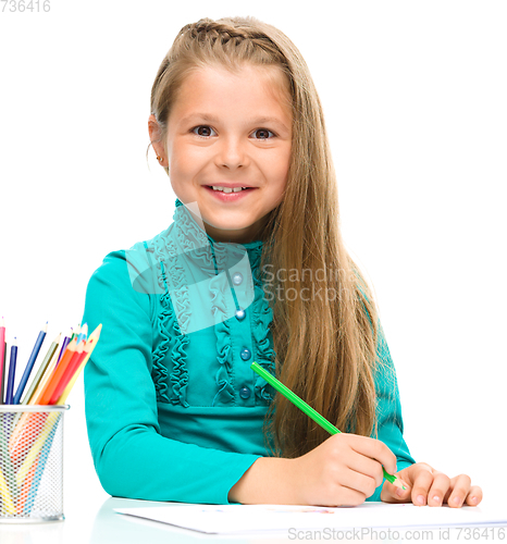 Image of Little girl is drawing using pencils