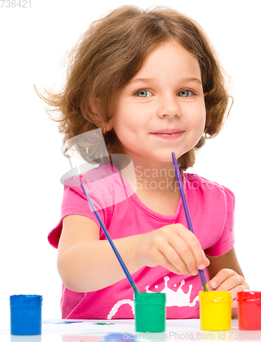 Image of Little girl is painting with gouache