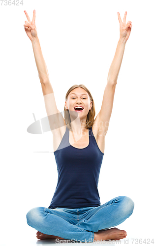 Image of Young happy woman is sitting on the floor