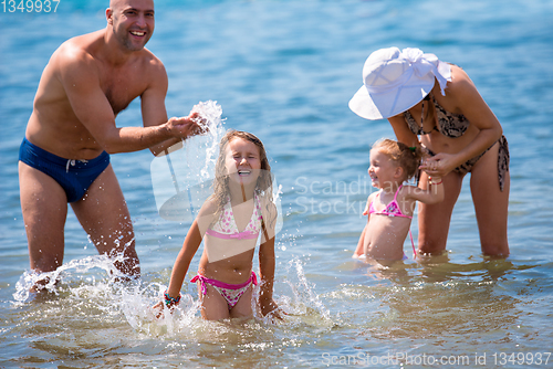 Image of happy family splashing each other at beach
