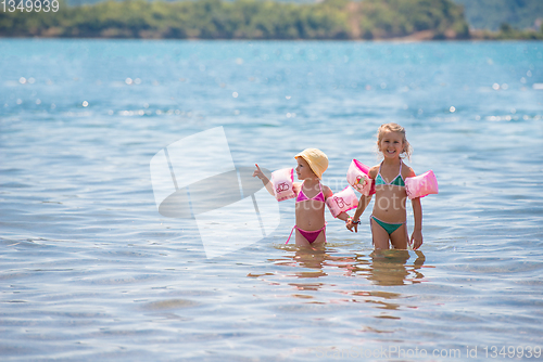 Image of little girls with swimming armbands playing in shallow water