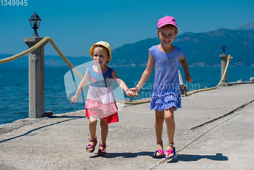 Image of little sisters running on the beach coast