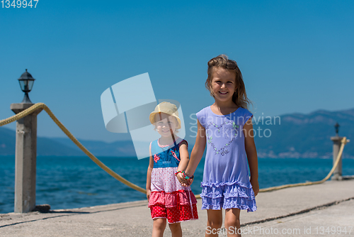 Image of little sisters walking on the beach coast