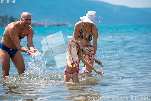 Image of happy family splashing each other at beach