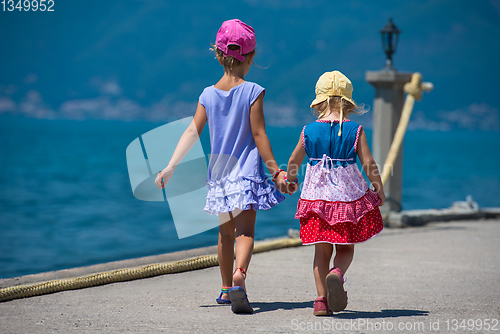 Image of little sisters walking on the beach coast