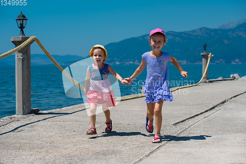 Image of little sisters running on the beach coast