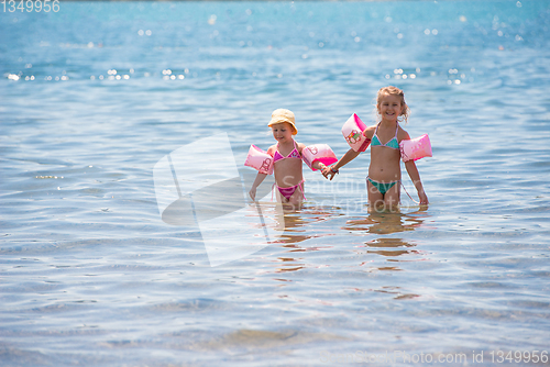 Image of little girls with swimming armbands playing in shallow water