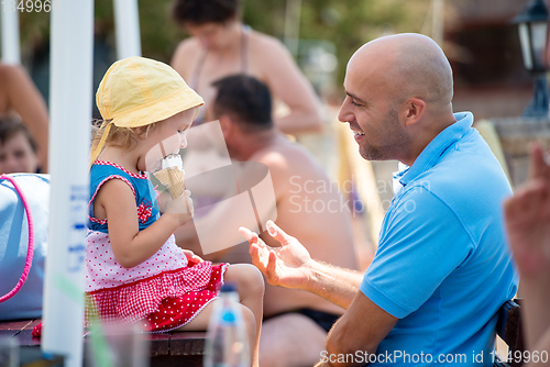 Image of cute little girl eating ice cream with her young father