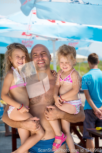 Image of portrait of young happy father with daughters by the sea