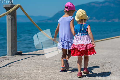 Image of little sisters walking on the beach coast