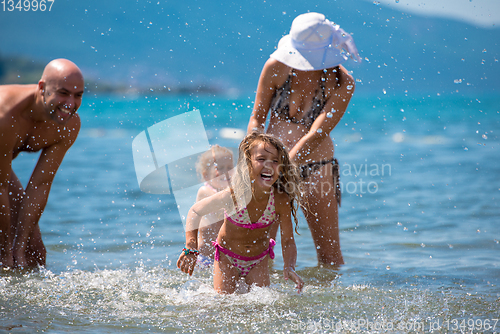 Image of happy family splashing each other at beach