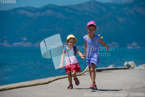 Image of little sisters running on the beach coast