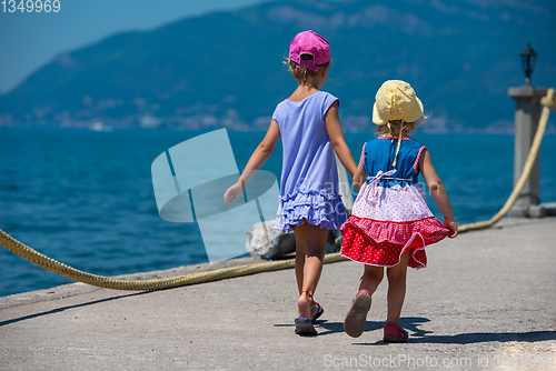 Image of little sisters walking on the beach coast