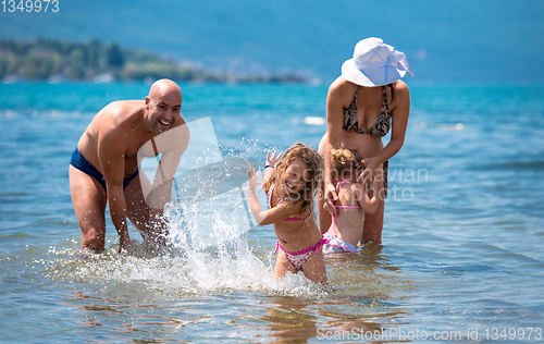 Image of happy family splashing each other at beach