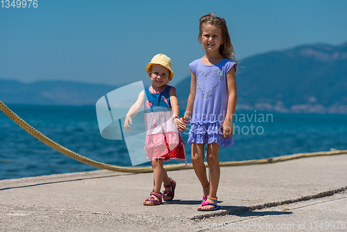 Image of little sisters walking on the beach coast