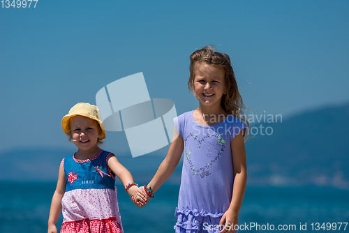 Image of little sisters walking on the beach coast