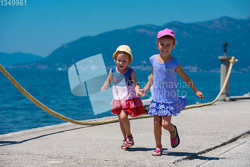 Image of little sisters running on the beach coast