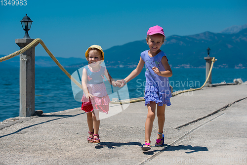 Image of little sisters running on the beach coast