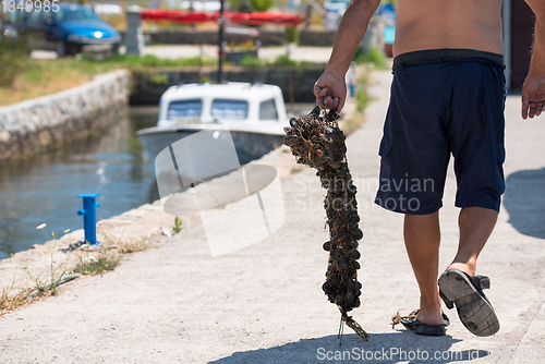 Image of senior man carries a bag of fresh mussel