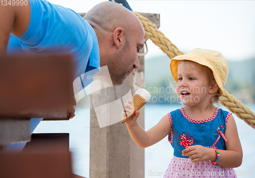 Image of cute little girl eating ice cream with her young father