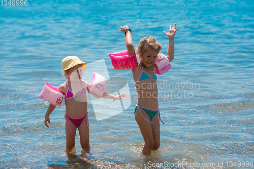 Image of little girls with swimming armbands playing in shallow water