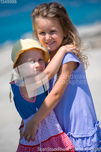 Image of little sisters hugging on the beach coast
