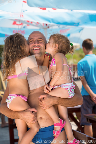 Image of portrait of young happy father with daughters by the sea