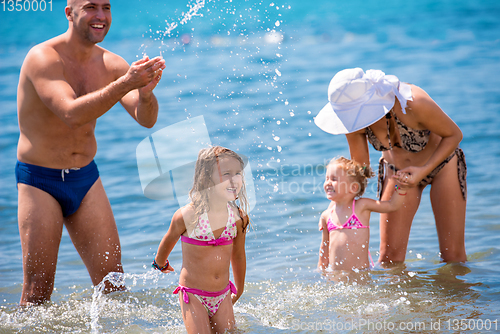 Image of happy family splashing each other at beach