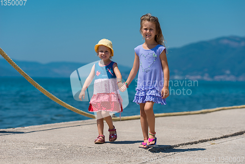 Image of little sisters walking on the beach coast