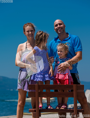 Image of portrait of young happy family with daughters by the sea