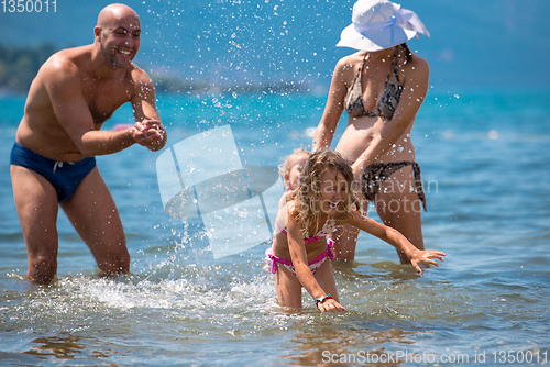 Image of happy family splashing each other at beach