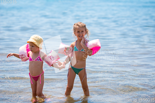 Image of little girls with swimming armbands playing in shallow water