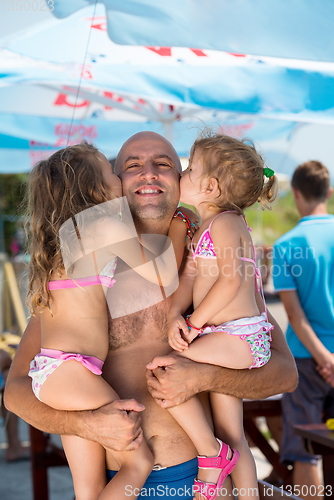 Image of portrait of young happy father with daughters by the sea