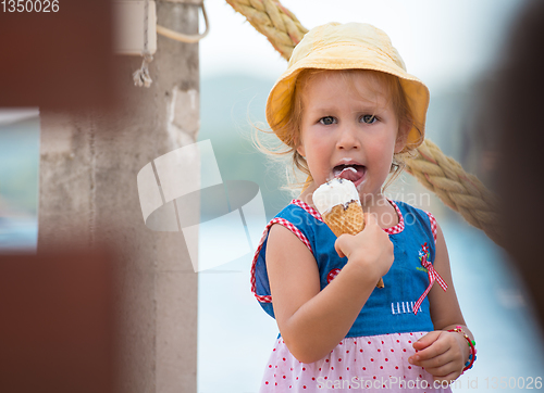 Image of little girl eating ice cream by the sea