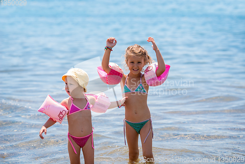 Image of little girls with swimming armbands playing in shallow water