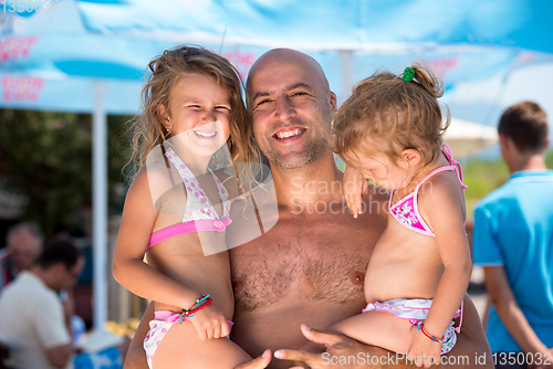 Image of portrait of young happy father with daughters by the sea