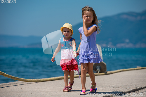 Image of little sisters walking on the beach coast