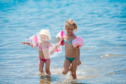 Image of little girls with swimming armbands playing in shallow water