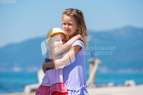 Image of little sisters hugging on the beach coast