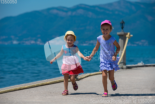 Image of little sisters running on the beach coast