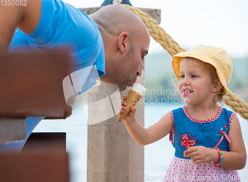 Image of cute little girl eating ice cream with her young father