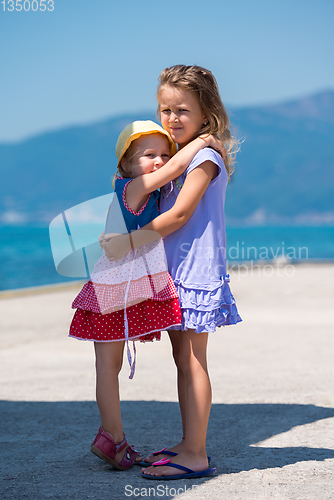 Image of little sisters hugging on the beach coast