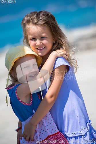Image of little sisters hugging on the beach coast